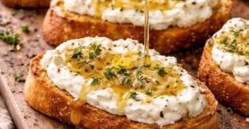 Crostinis croustillants garnis de feta fouettée onctueuse, nappés de miel piquant et décorés de thym frais