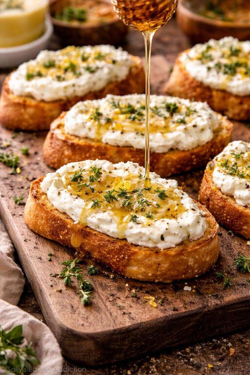 Crostinis croustillants garnis de feta fouettée onctueuse, nappés de miel piquant et décorés de thym frais