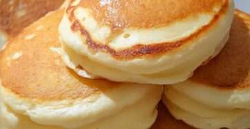 Pile de pancakes maison épais et moelleux servis chauds avec sirop d’érable et beurre sur une assiette