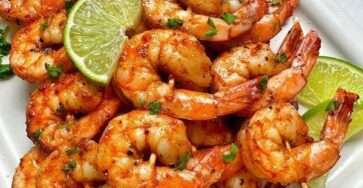 Brochettes de crevettes grillées dorées au citron vert et paprika fumé, garnies de coriandre fraîche, servies avec quartiers de lime.