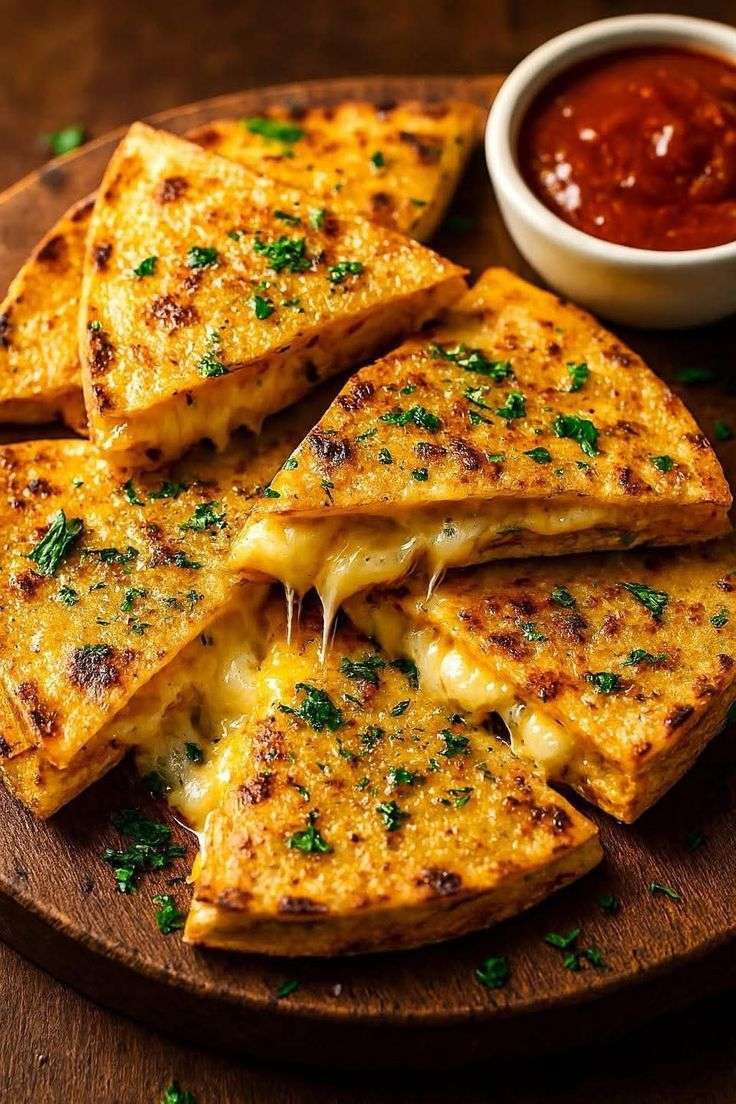 Quesadillas dorées au beurre à l’ail avec fromage mozzarella et cheddar fondant, coupées en triangles et garnies de persil frais, servies avec sauce tomate.