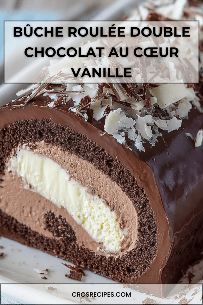 Bûche roulée au chocolat nappée d’un glaçage brillant, garnie d’un cœur vanille visible à la coupe et décorée de copeaux de chocolat noir et blanc