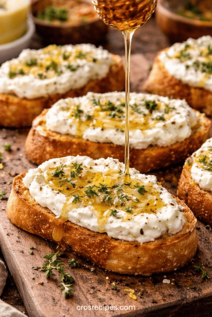 Crostinis croustillants garnis de feta fouettée onctueuse, nappés de miel piquant et décorés de thym frais