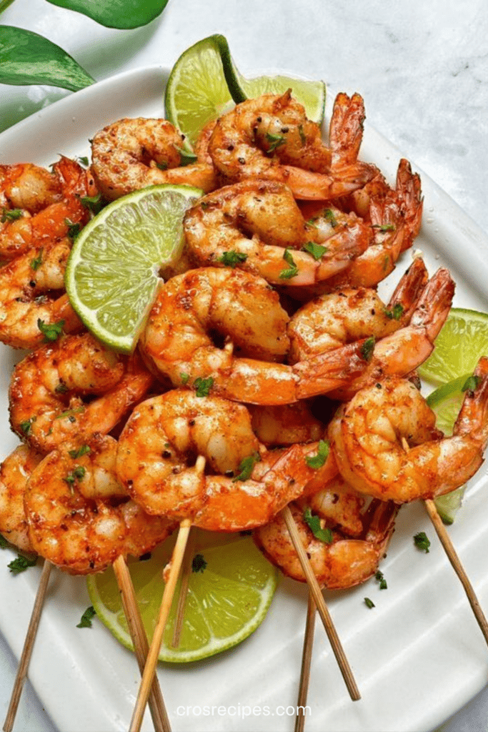 Brochettes de crevettes grillées dorées au citron vert et paprika fumé, garnies de coriandre fraîche, servies avec quartiers de lime.