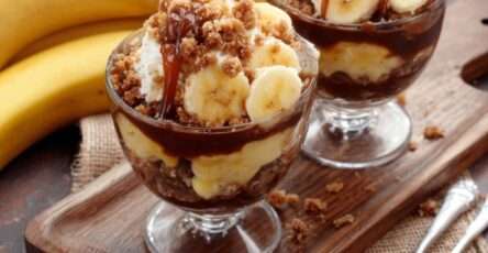 Verrines banane avec crème vanille onctueuse, caramel nappant et crumble biscuité croustillant, présentées en couches visibles.