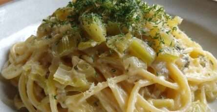 Assiette de pâtes crémeuses longues nappées d’une sauce crémeuse aux poireaux fondants et citron, garnie d’herbes fraîches et zeste de citron.