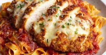 Escalope de poulet parmigiana gratinée à la mozzarella et parmesan, servie sur des tagliatelles nappées de sauce tomate italienne.