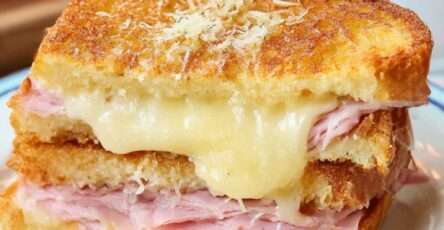 Croque-monsieur doré et croustillant au jambon blanc et fromage fondu, servi chaud avec salade verte sur table en bois.