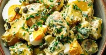 Salade de pommes de terre nouvelles aux œufs durs et câpres, mélangée à une sauce crémeuse à la ciboulette, servie froide dans un saladier.