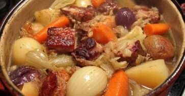 Potée savoyarde traditionnelle en cocotte avec chou vert, palette de porc, saucisses fumées, carottes et pommes de terre servie bien chaude.