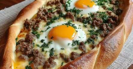 Pide turque en forme de bateau garnie de viande hachée, fromage fondu et œufs coulants, cuite au four et parsemée de persil frais.