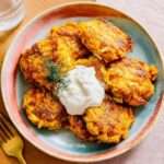 Galettes de légumes dorées au four à base de carottes et courgettes, servies avec une sauce yaourt citronnée aux herbes fraîches.