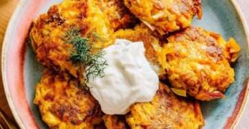 Galettes de légumes dorées au four à base de carottes et courgettes, servies avec une sauce yaourt citronnée aux herbes fraîches.