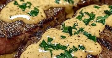 Steak au poivre de bœuf épais enrobé de poivre concassé, nappé de sauce crémeuse au poivre dans une poêle en fonte, servi chaud avec persil frais.