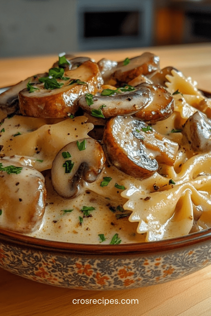 Farfalles enrobées de sauce crémeuse aux champignons poêlés, persil frais et parmesan, servies bien chaudes dans une assiette creuse