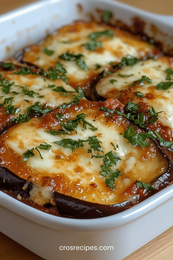 Gratin d’aubergines maison aux tomates concassées, mozzarella fondante et parmesan doré, servi chaud dans un plat à gratin.