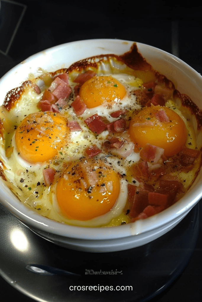 Œufs cocotte cuits au four en ramequins avec fromage de chèvre fondant, lardons fumés croustillants et jaune légèrement coulant.