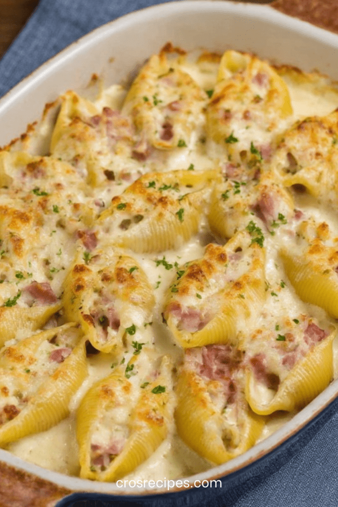 Conchiglioni farcis au jambon nappés de béchamel onctueuse et fromage gratiné, servis bien chauds dans un plat à gratin doré.
