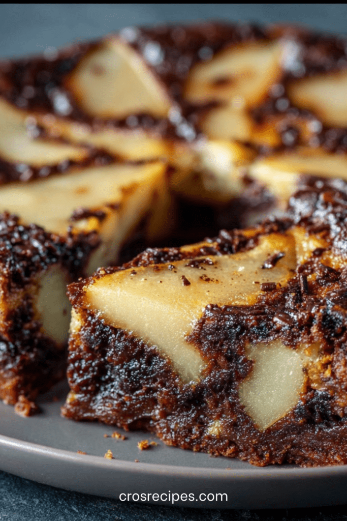 Clafoutis aux poires et chocolat noir dans un moule rond, texture fondante entre flan et gâteau, saupoudré de sucre glace.