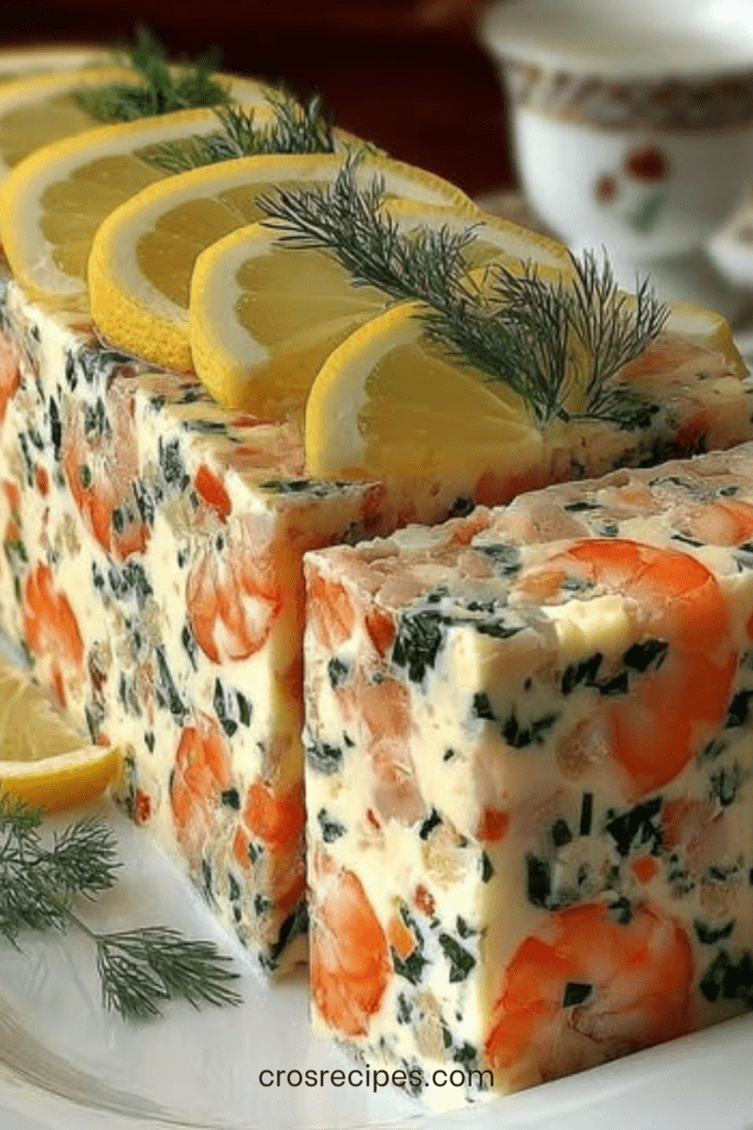 Terrine de crevettes rose pâle tranchée, texture crémeuse et lisse, parsemée d’aneth et de ciboulette, décorée de fines tranches de citron frais.