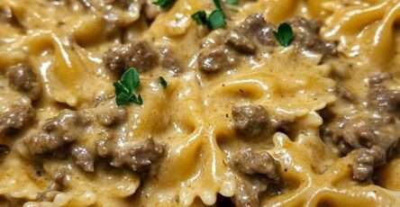 Pâtes papillon à la viande hachée nappées de sauce crémeuse au parmesan, texture onctueuse visible, servies chaudes avec persil frais