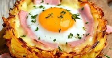 Nid de pommes de terre croustillants garnis de fromage à raclette fondant, jambon et œuf coulant, dorés au four et servis chauds