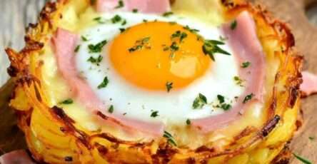 Nid de pommes de terre croustillants garnis de fromage à raclette fondant, jambon et œuf coulant, dorés au four et servis chauds