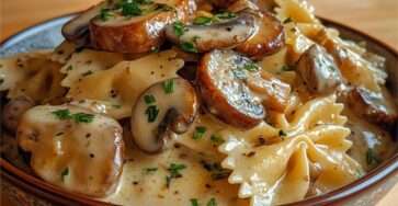 Farfalles enrobées de sauce crémeuse aux champignons poêlés, persil frais et parmesan, servies bien chaudes dans une assiette creuse