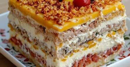 Gâteau salé en couches de pain de mie garni de crème au thon, mangue et tomate, décoré d’herbes fraîches et tomates cerises pour buffet