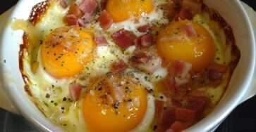 Œufs cocotte cuits au four en ramequins avec fromage de chèvre fondant, lardons fumés croustillants et jaune légèrement coulant.