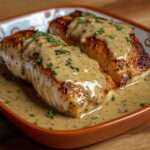 Pavés de saumon poêlés nappés de sauce crème moutardée aux herbes, servis bien chauds dans une poêle.