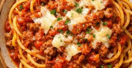 Spaghetti bolognaise maison avec sauce tomate mijotée au bœuf, parmesan râpé et persil frais, servis bien chauds dans une assiette généreuse.
