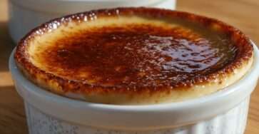 Crème brûlée vanillée maison avec croûte de sucre caramélisée dorée, servie dans un ramequin élégant, texture lisse et fondante.