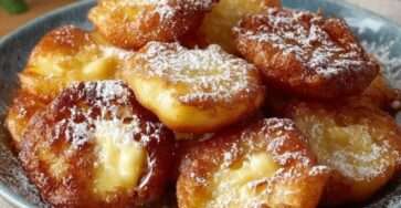 Beignets de pommes dorés à la poêle, saupoudrés de sucre glace, servis chauds sur une assiette, texture croustillante et cœur fondant.