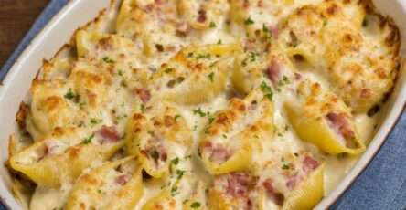 Conchiglioni farcis au jambon nappés de béchamel onctueuse et fromage gratiné, servis bien chauds dans un plat à gratin doré.
