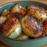 Tranches épaisses de chou rôti au four, bords grillés et caramélisés, parsemées de persil frais sur une plaque de cuisson.