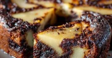 Clafoutis aux poires et chocolat noir dans un moule rond, texture fondante entre flan et gâteau, saupoudré de sucre glace.