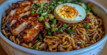 Bol de ramen au chashu avec bouillon shoyu foncé, nouilles ramen fraîches, tranches de poitrine de porc braisée caramélisée, œuf mollet coupé en deux, oignons verts et graines de sésame.