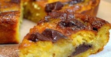 Clafoutis banane chocolat maison dans un moule beurré, bananes en rondelles et morceaux de chocolat noir fondants, surface dorée et légèrement gonflée à la sortie du four.