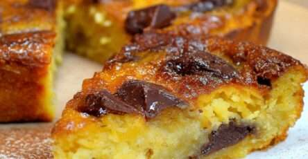 Clafoutis banane chocolat maison dans un moule beurré, bananes en rondelles et morceaux de chocolat noir fondants, surface dorée et légèrement gonflée à la sortie du four.