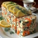 Terrine de crevettes rose pâle tranchée, texture crémeuse et lisse, parsemée d’aneth et de ciboulette, décorée de fines tranches de citron frais.