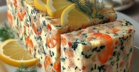 Terrine de crevettes rose pâle tranchée, texture crémeuse et lisse, parsemée d’aneth et de ciboulette, décorée de fines tranches de citron frais.