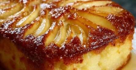 Gâteau aux pommes moelleux et doré, décoré de fines lamelles disposées en rosace, légèrement caramélisé sur le dessus, servi sur une assiette claire avec texture fondante visible à la découpe.