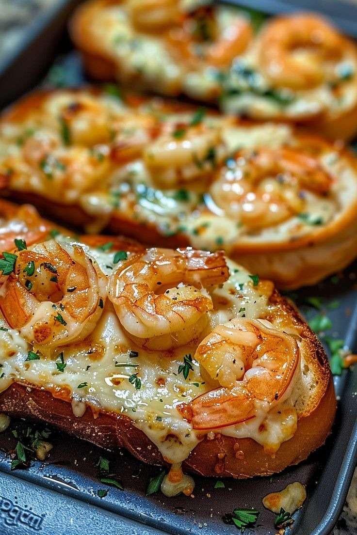 Tartines gratinées aux crevettes dorées à l’ail et fromage fondu, légèrement gratinées et parsemées de persil frais sur une plaque de cuisson.