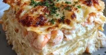 Plat de lasagnes aux fruits de mer gratinées, couches visibles de pâtes fondantes, crème onctueuse, crevettes et chair de crabe sous une croûte dorée de mozzarella et parmesan.