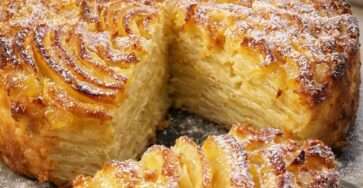 Gâteau ouragan aux pommes coupé en parts, fines tranches de pommes superposées formant un effet tourbillonnant, texture fondante et surface légèrement dorée saupoudrée de sucre glace.