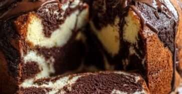 Gâteau marbré à la ricotta et au double chocolat nappé de glaçage au chocolat, décoré de copeaux de chocolat noir, présenté sur une assiette avec une texture moelleuse et un marbrage visible à la découpe.