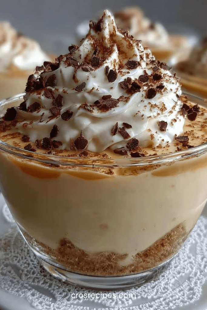 Verrines de crème au café surmontées de chantilly maison, avec biscuits émiettés et copeaux de chocolat, présentées en couches élégantes.