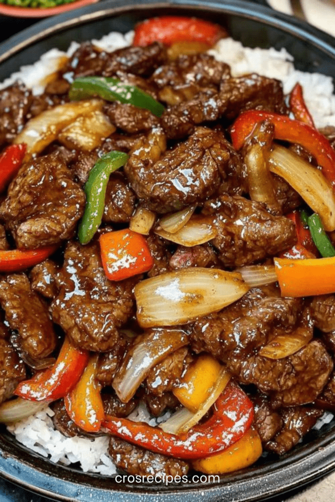 Assiette de bœuf aux poivrons à la chinoise avec lamelles de bœuf sautées, poivrons colorés, oignons fondants, sauce brillante et riz blanc servi chaud.