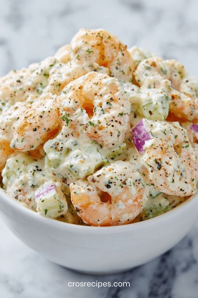 Bol de salade de crevettes façon deli new-yorkais avec mayonnaise, céleri croquant, oignon rouge et herbes fraîches, servi sur pain grillé.